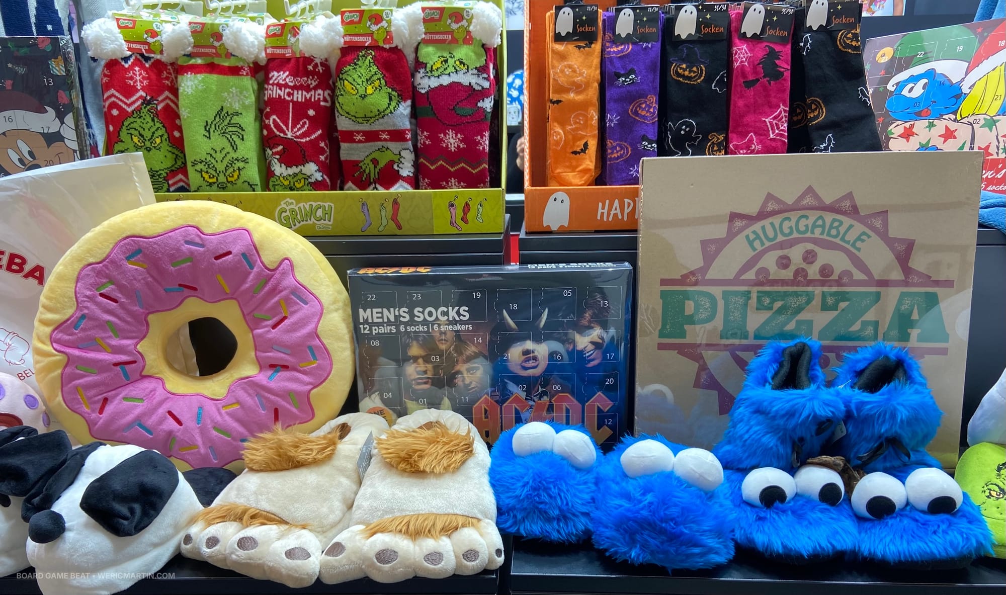 A retailer display of socks, slippers, a stuffed donut, and a box labeled "Huggable Pizza"