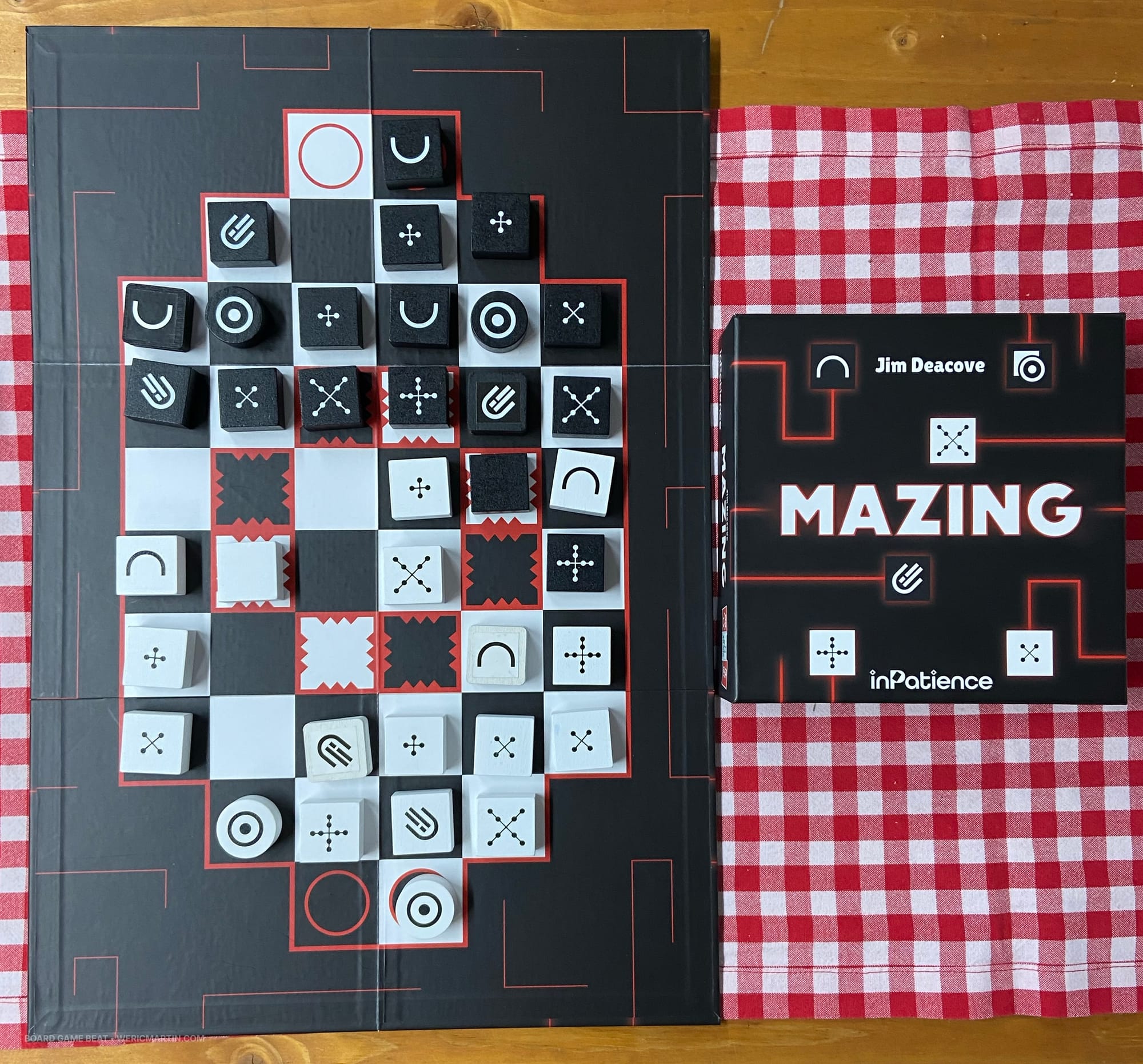 Front cover of the game Mazing next to the game board, which shows black pieces and white pieces with a variety of symbols