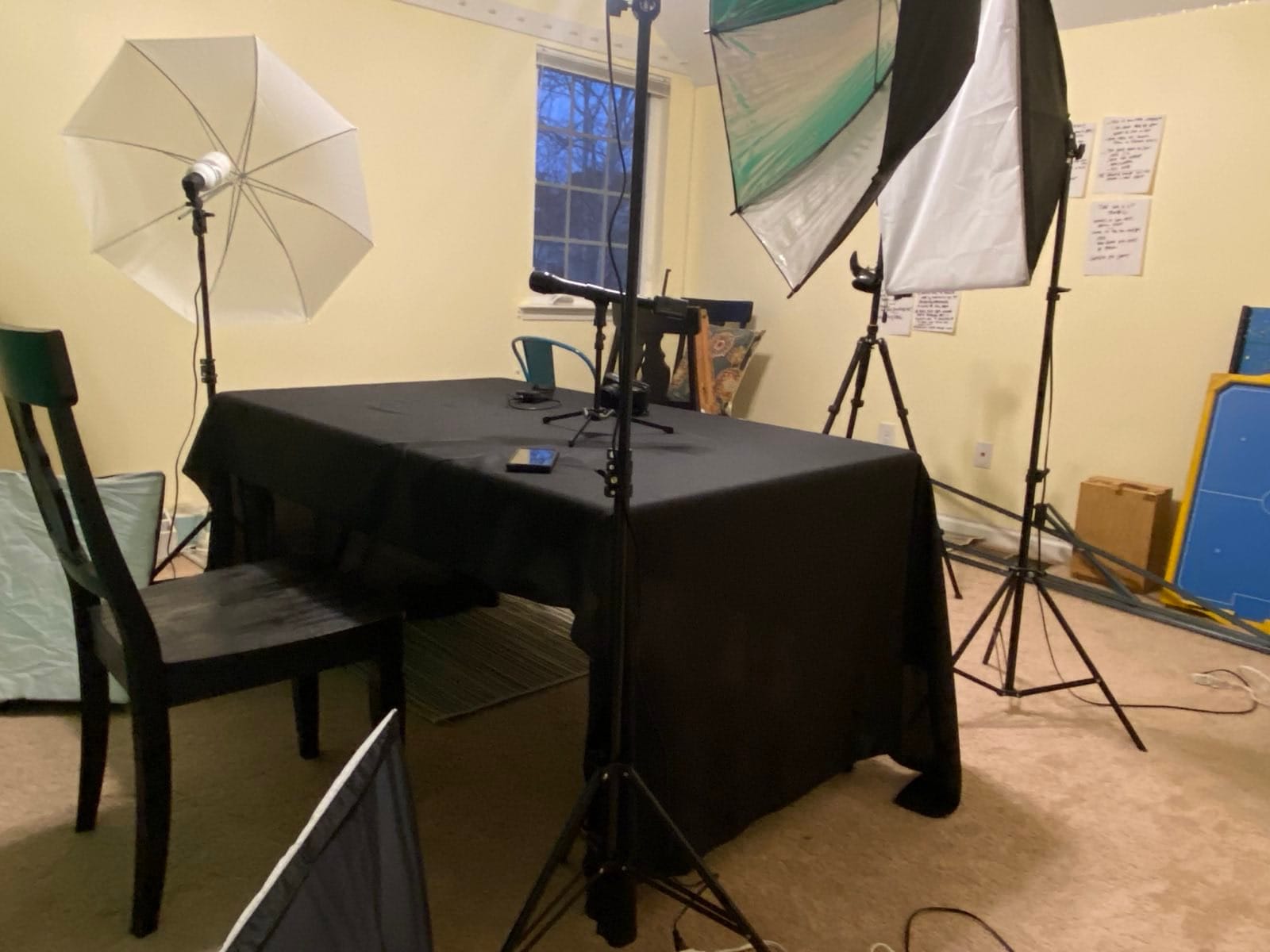 A table covered with a cloth is surrounded by multiple lights on stands and on the floor