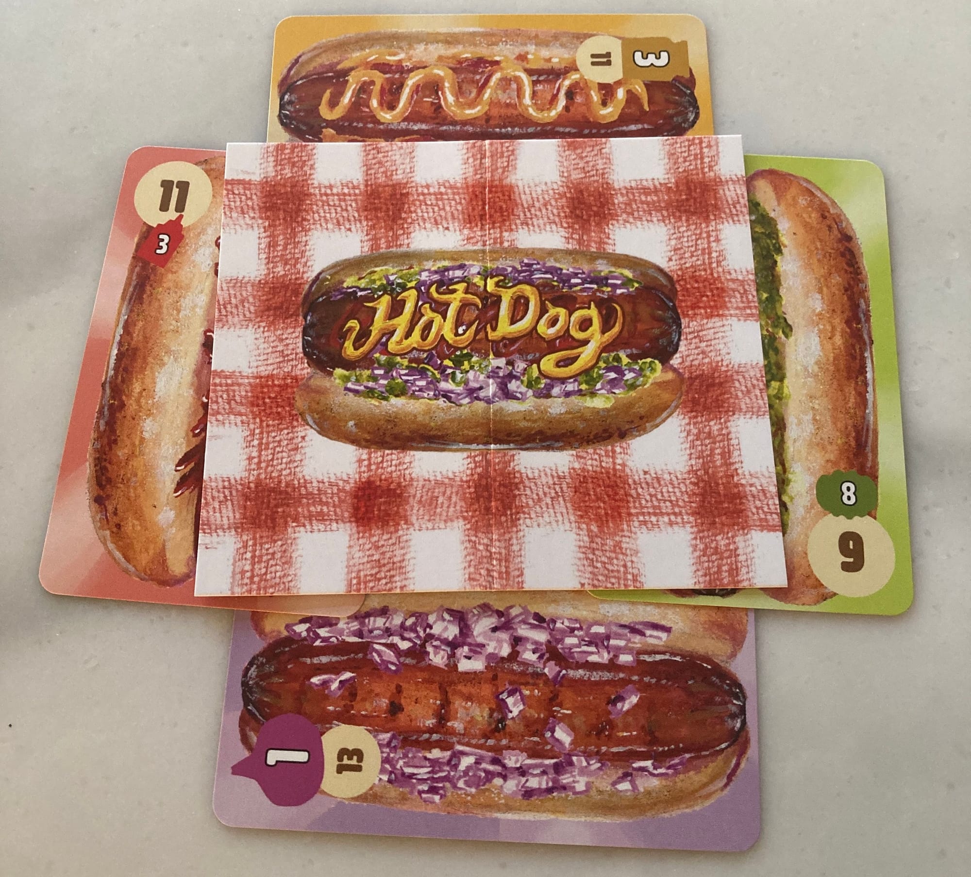 Four playing cards are tucked under a paper table so that only one of the card values is visible