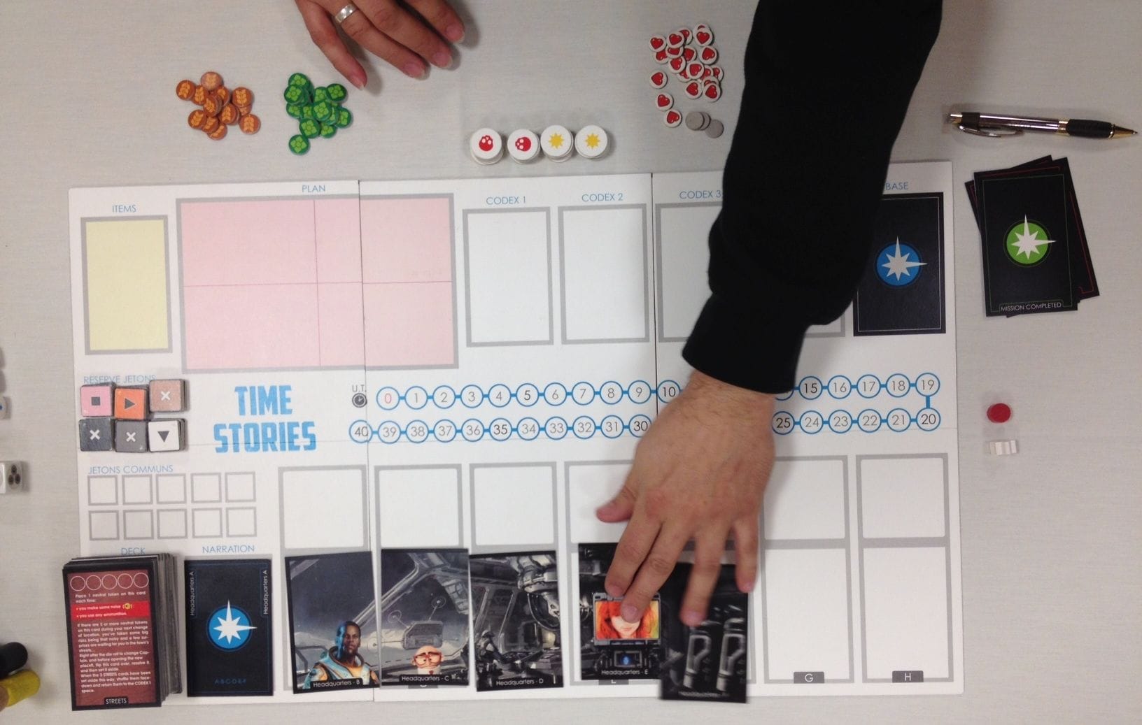 A homemade-looking game board that says "TIME STORIES" with a hand placing cards on it