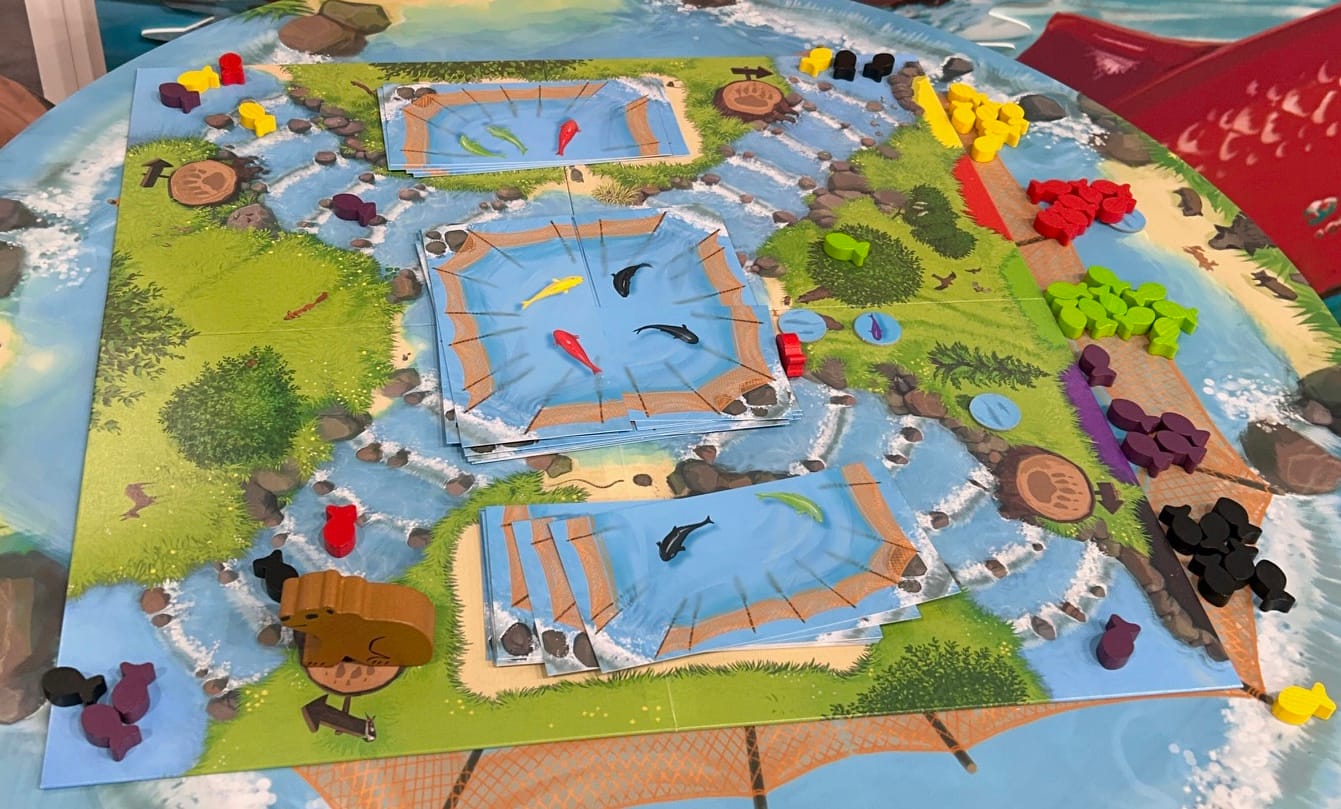 A game board shows a central pond, with tributaries running to the corners of the board and salmon swimming up them