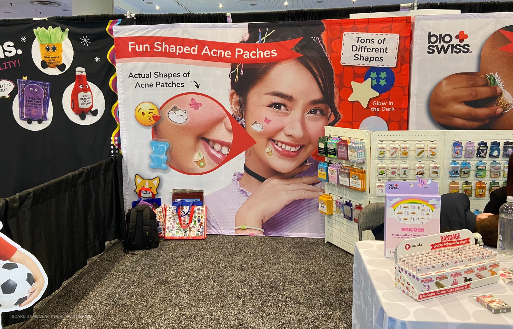A banner in a trade show booth reads "Fun shaped acne patches" and shows a teenage girl with several cartoony patches on her face