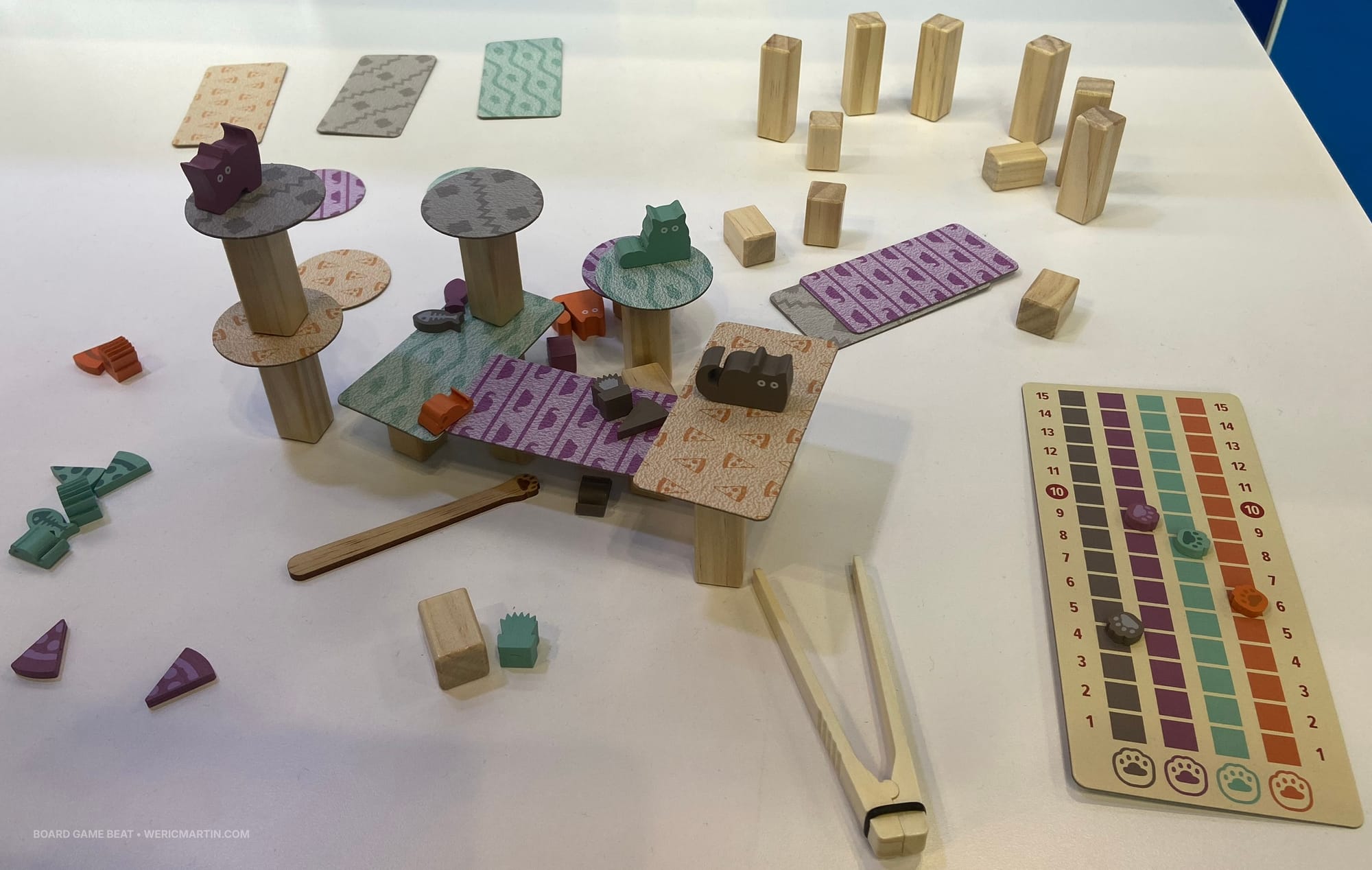 Components for the game Cats Knocking Things Off Ledges: tweezers, wooden cats and toys, platforms, pillars, a wooden cat's paw, and a scoreboard