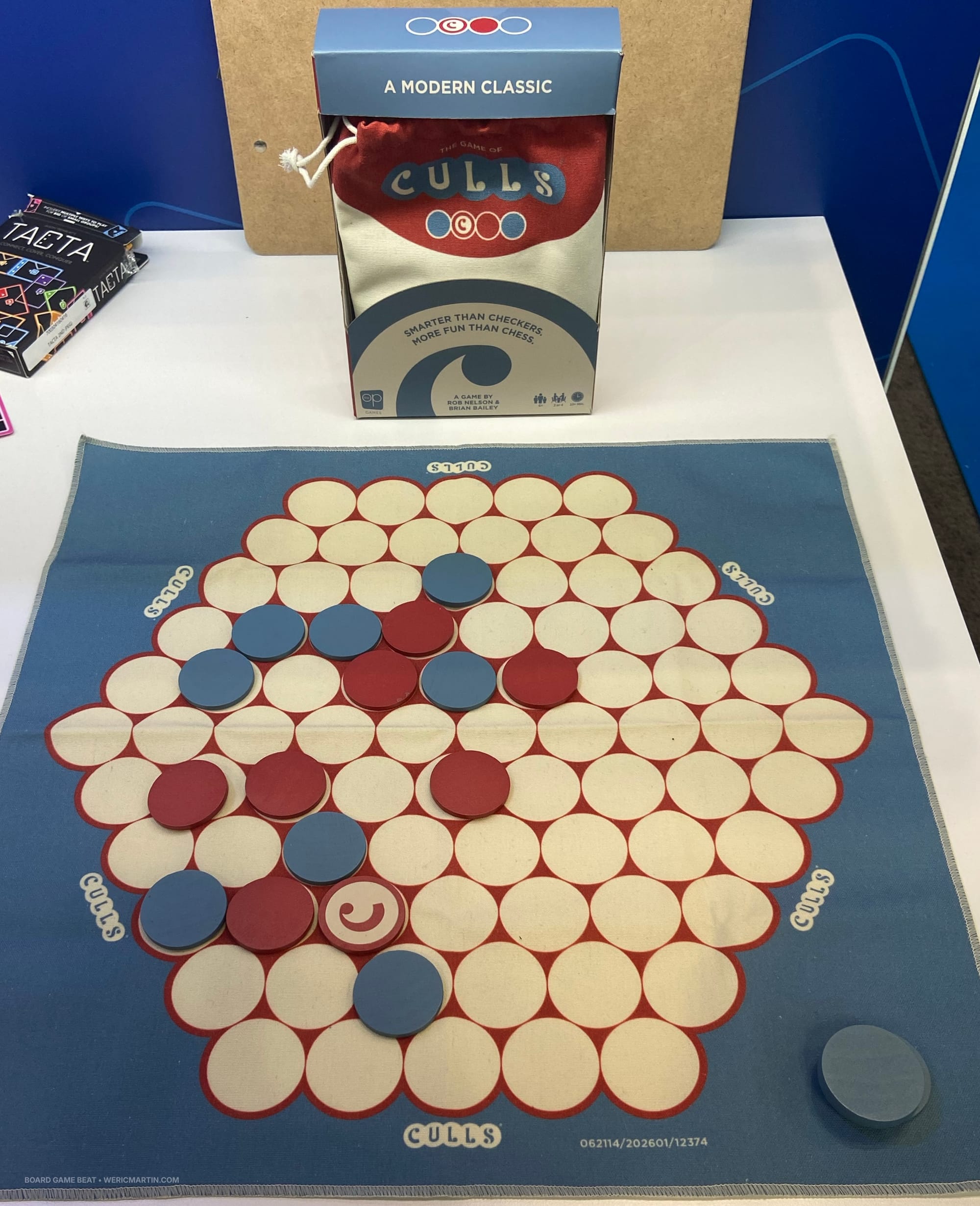 A cloth game board has discs in red and blue placed in spaces in a large hexagonal grid