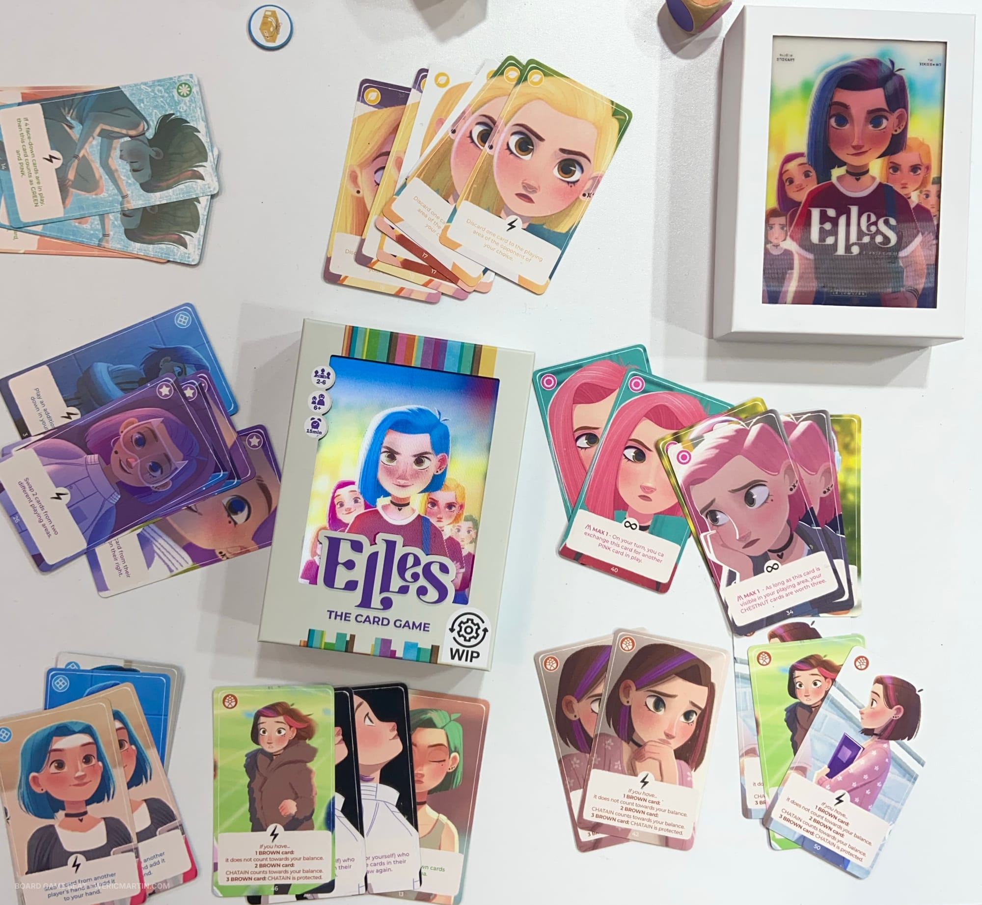 Two boxes for a card game named Elles, with sample cards each showing an image and card effect