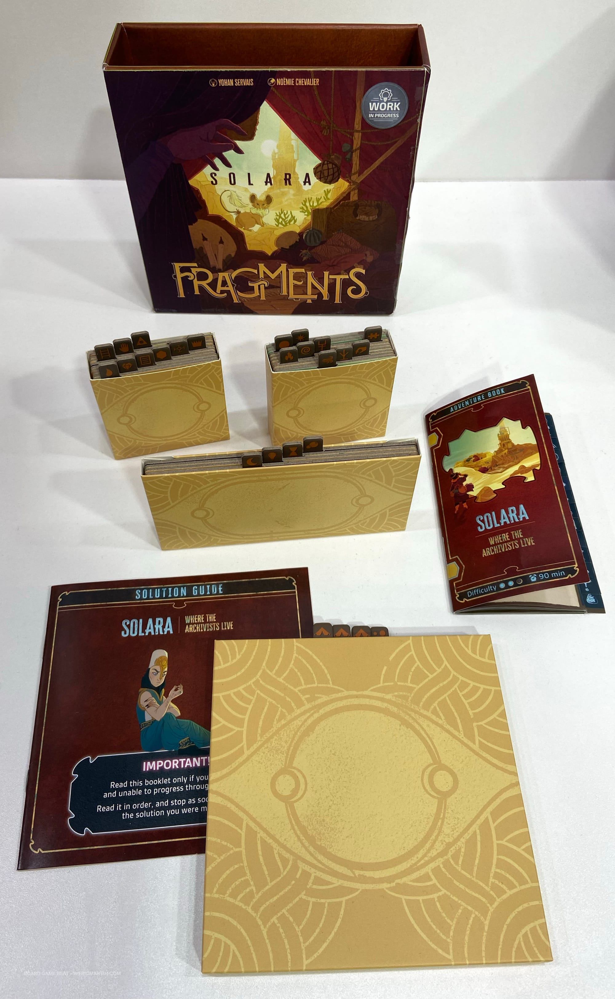 Game box for Fragments: Solara, three trays containing small cardboard tiles, an adventure book, and a solution guide