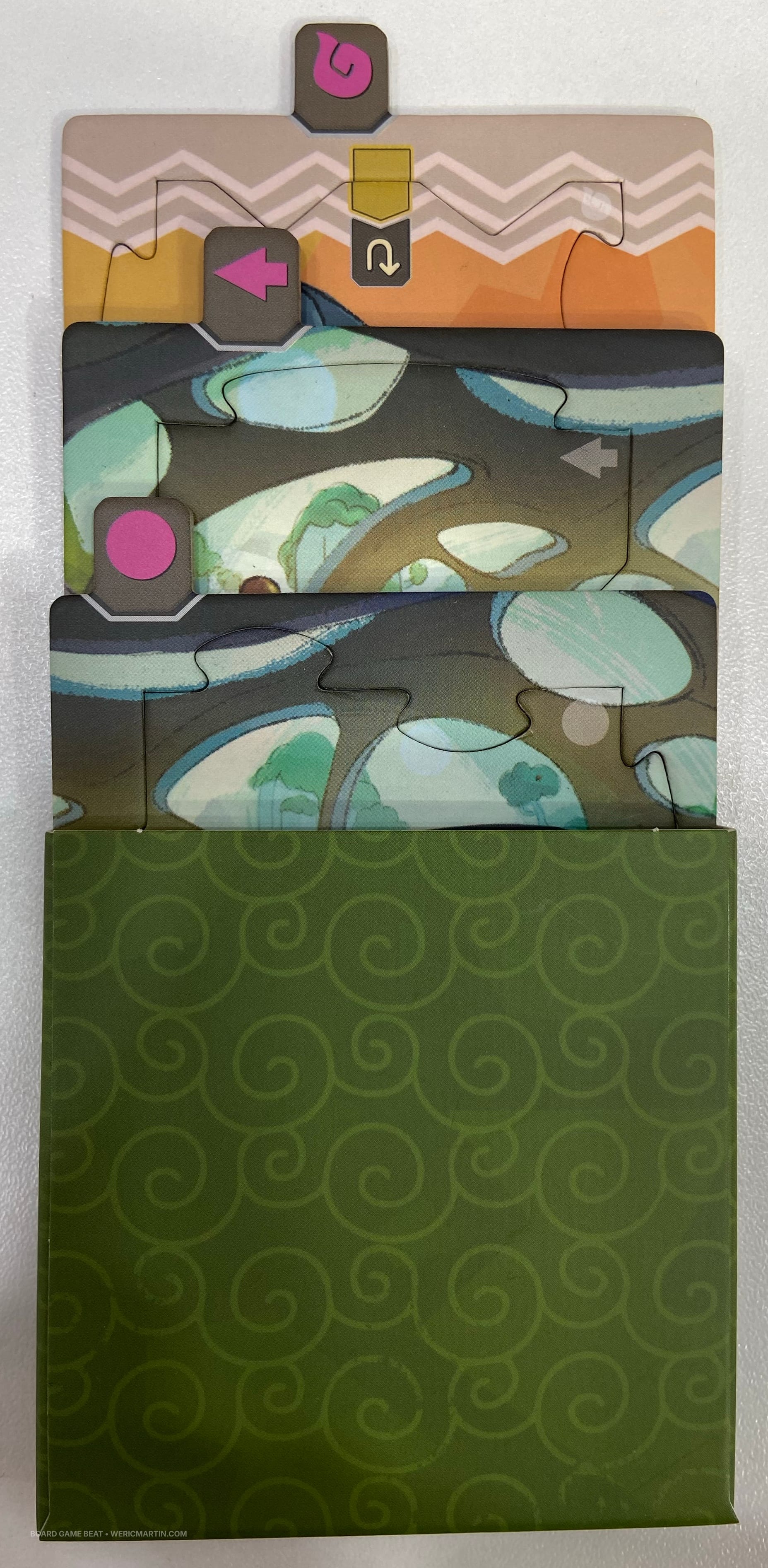 Three puzzle pieces are pulled partially out of the cardboard sleeve