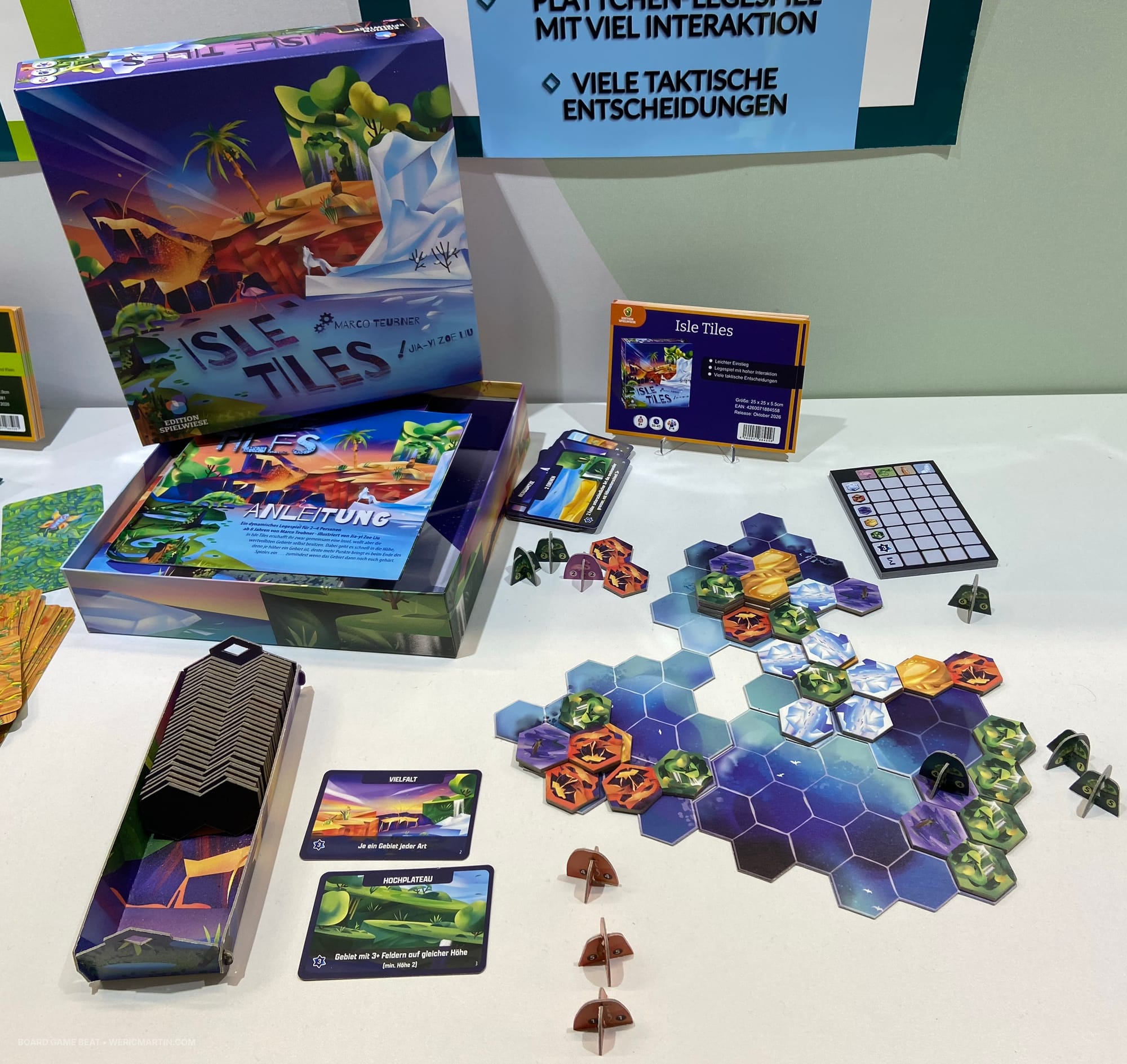 Front cover of the game Isle Tiles, along with a hex-based game board covered with domino tiles comprised of two hexes