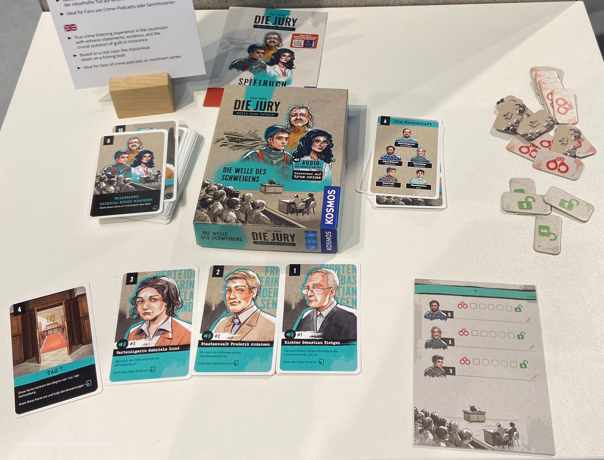 The game box is surrounded by cards featuring characters in the trial, as well as various tokens