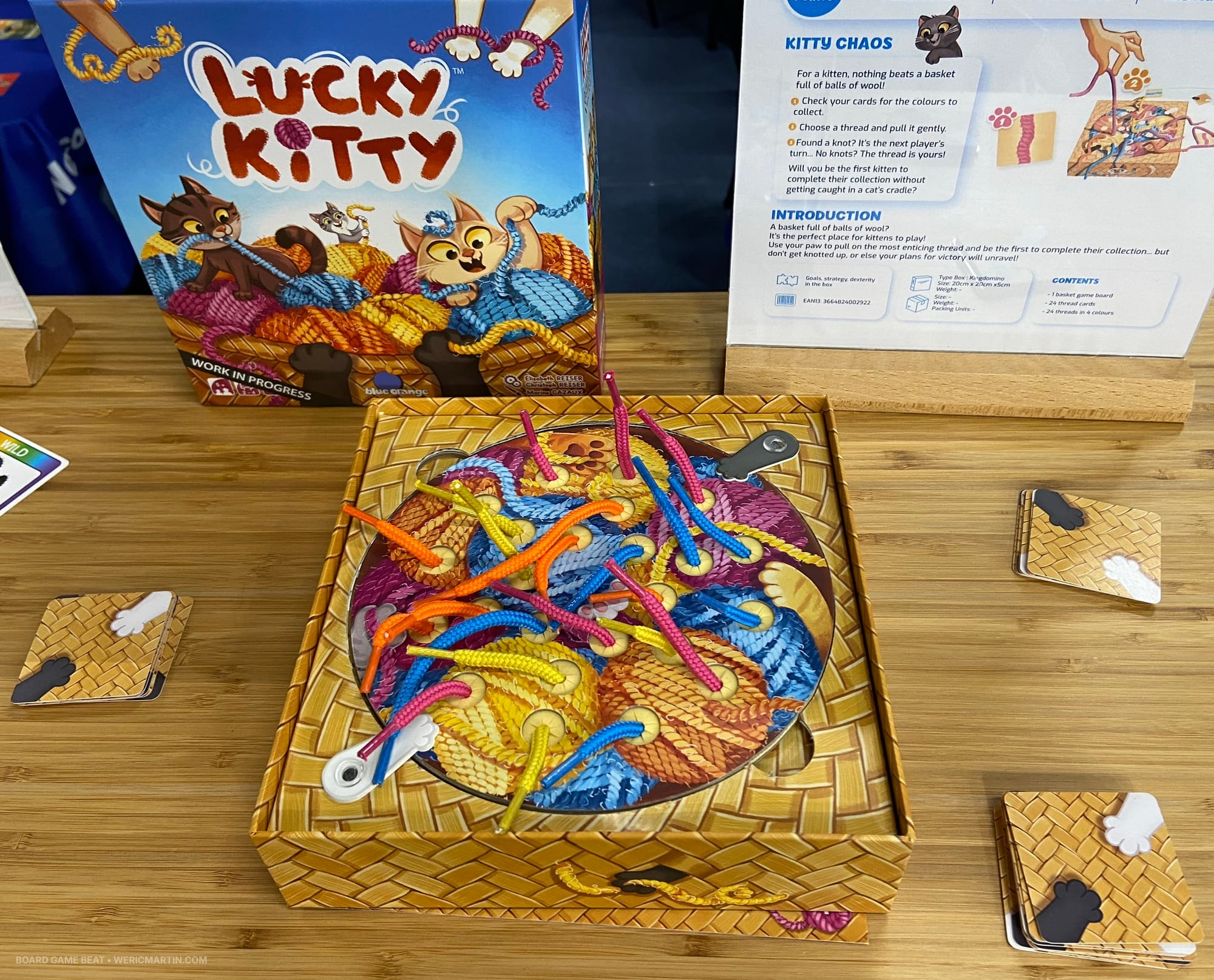 A game box has a lot of shoelace ends sticking through holes in a piece of card that covers the box opening