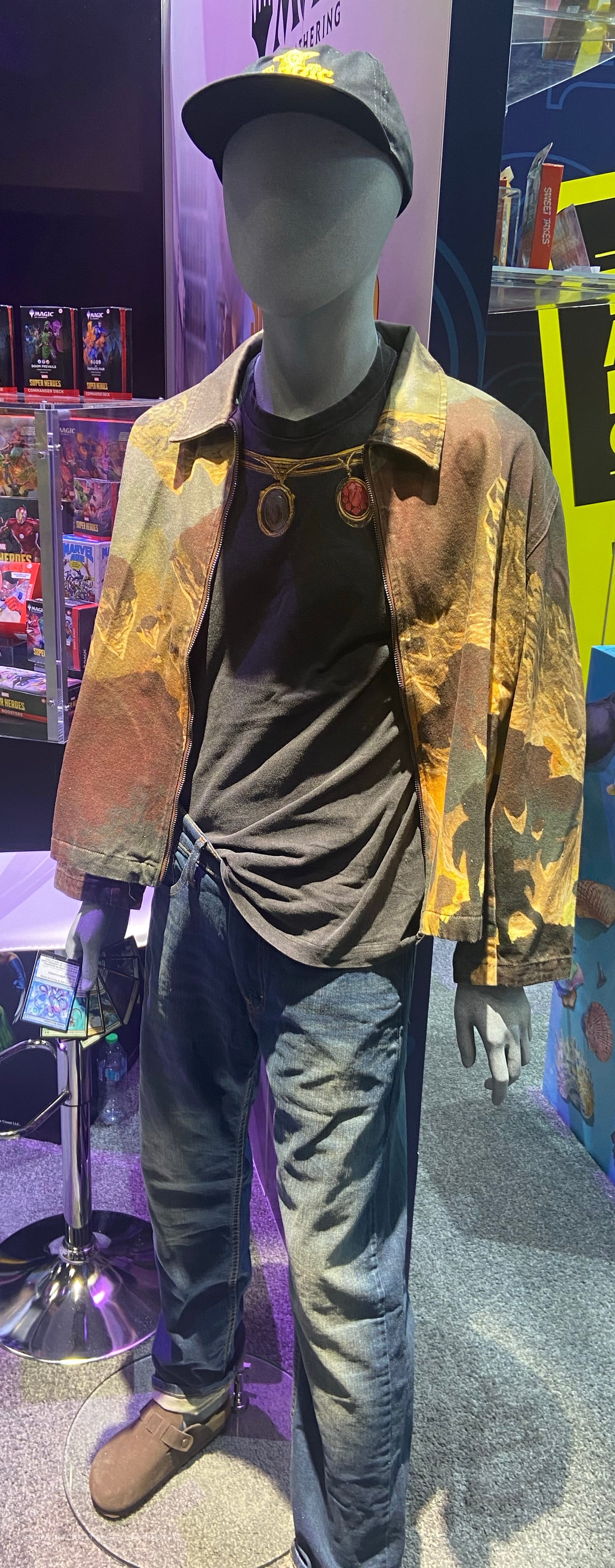 A mannequin wears Magic: The Gathering themed clothing and holds a hand of Magic cards