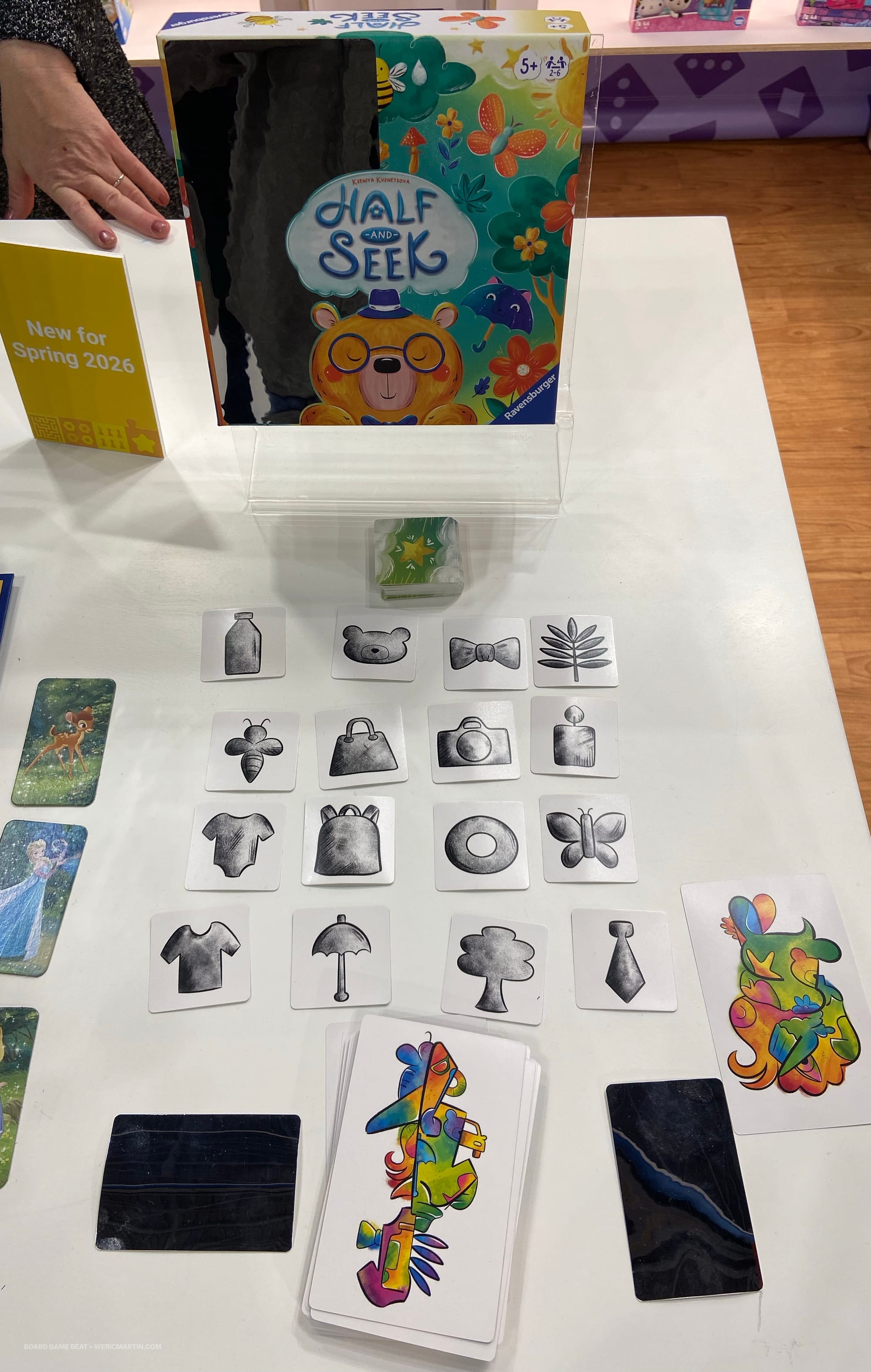 Sixteen cards showing images in shades of gray are laid out next to a deck of cards, each with a colorful, surreal image