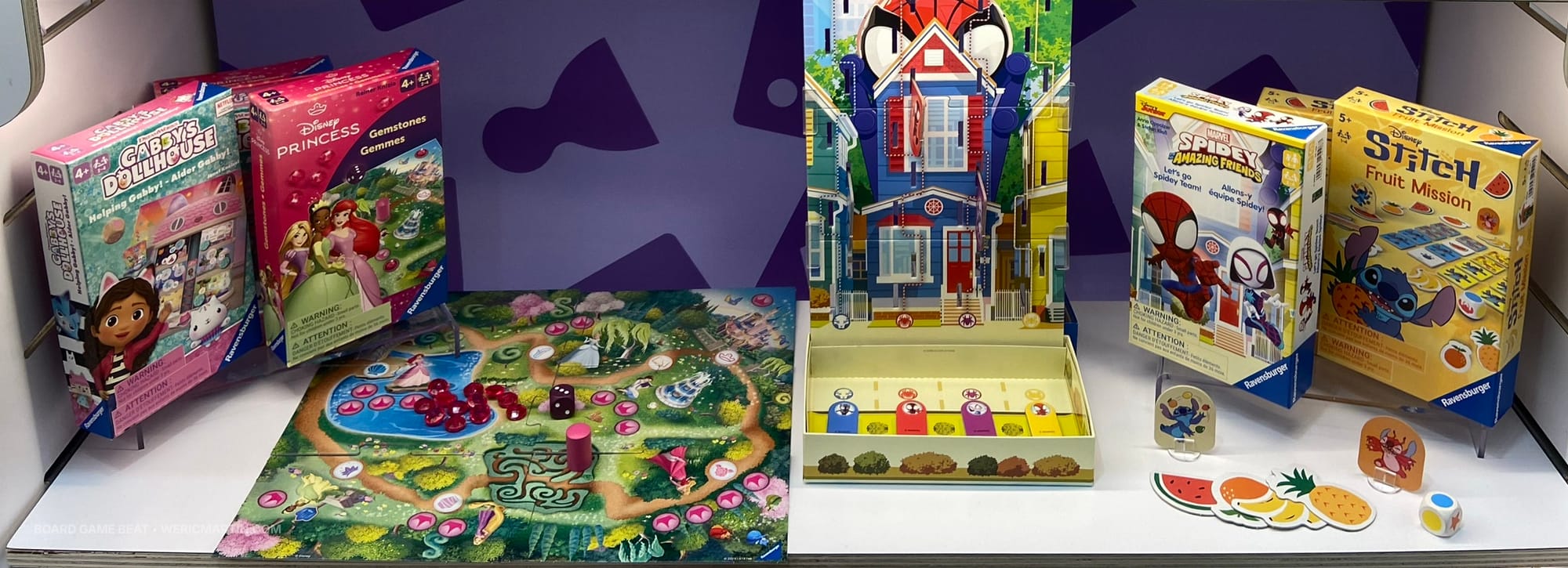 Four small game boxes are on a shelf, along with a tiny game board and cardboard components