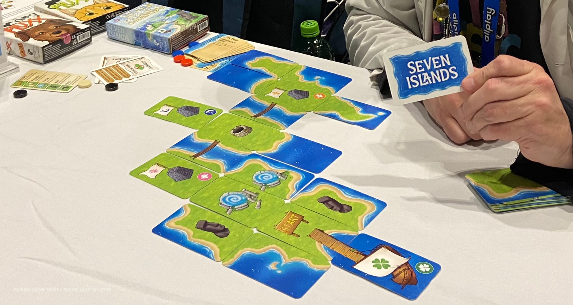 Cards are laid adjacent to one another on the table to create a chain of islands, with various cards featuring towers, portals, moai, and wells